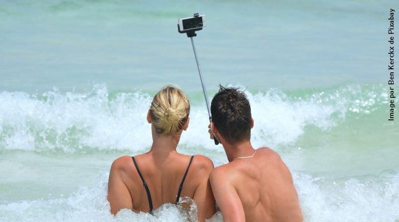 Couple de dos à la plage prenant un selfie