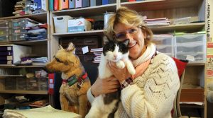 Corinne Legrand, présidente et fondatrice du refuge Un Gîte une Gamelle en compagnie de son directeur Félix le chat et du chien en peluche, la mascotte du refuge.
